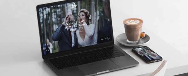 laptop i smartphone z otwartą stroną internetową Klipy Weselne na biurku, obok kawa