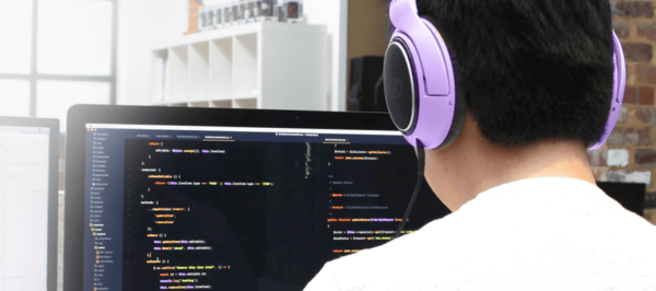 programista w słuchawkach przed monitorem