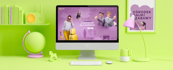 monitor z otwartą stroną internetową ośrodka nauki i zabawy Skool na biurku, obok lampka, kubek, globus