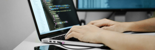 programista pisze kod na laptopie