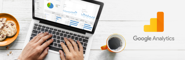 laptop z dłońmi na klawiaturze, obok logo Google Analytics