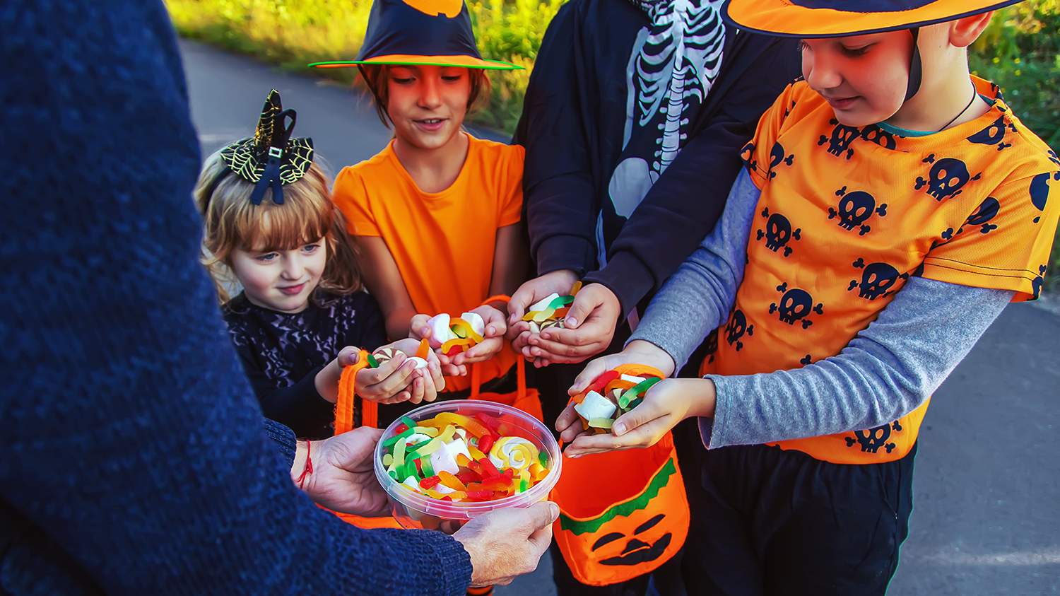 Dzieci przebrane w halloweenowe stroje zbierają słodycze podczas zabawy cukierek albo psikus.