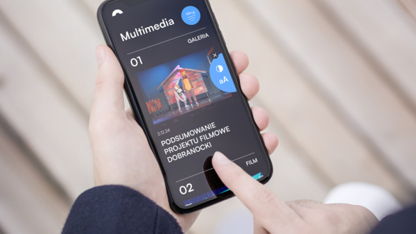 Smartfon trzymany w dłoniach, a na jego ekranie widać opcję dostosowania wielkości czcionki i koloru wyświetlania ekranu.