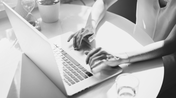 Osoba pracująca przy laptopie w świetle dziennym, praca biurowa.