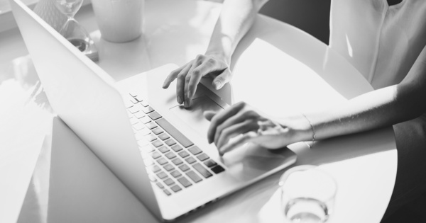 Osoba pracująca przy laptopie w świetle dziennym, praca biurowa.