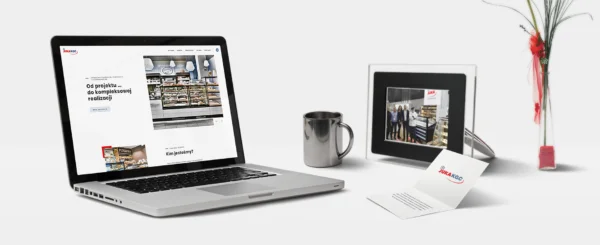 laptop z otwartą stroną internetową firmy Juka KGC, obok kubek i ramka ze zdjęciem