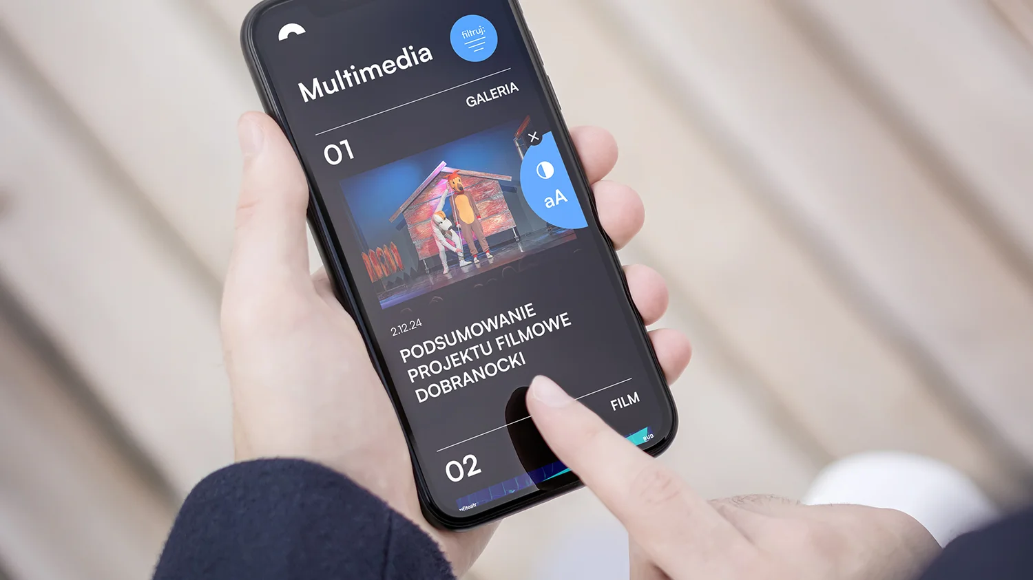 Smartfon trzymany w dłoniach, a na jego ekranie widać opcję dostosowania wielkości czcionki i koloru wyświetlania ekranu.