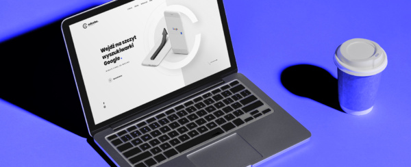 laptop z otwartą stroną internetową firmy Adcube, obok kubek