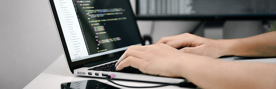 Programista piszący kod na klawiaturze laptopa podczas tworzenia aplikacji