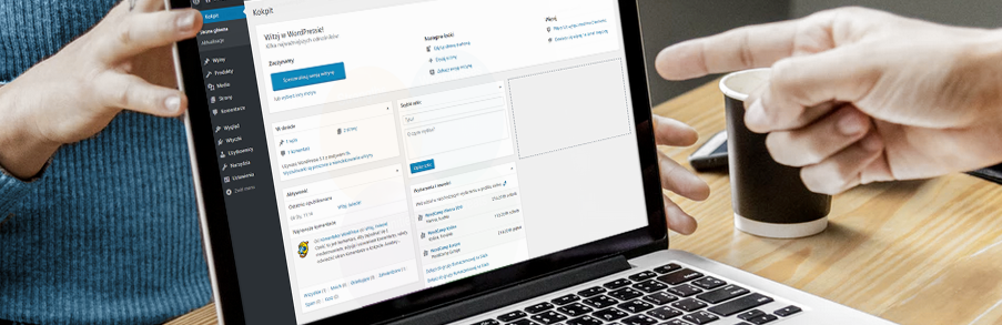 Dwie osoby omawiające pulpit administratora WordPress wyświetlony na ekranie laptopa