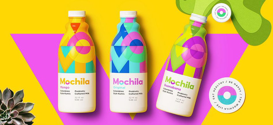 Trzy butelki mleka probiotycznego Mochila w kolorowych, geometrycznych opakowaniach na żółtym tle