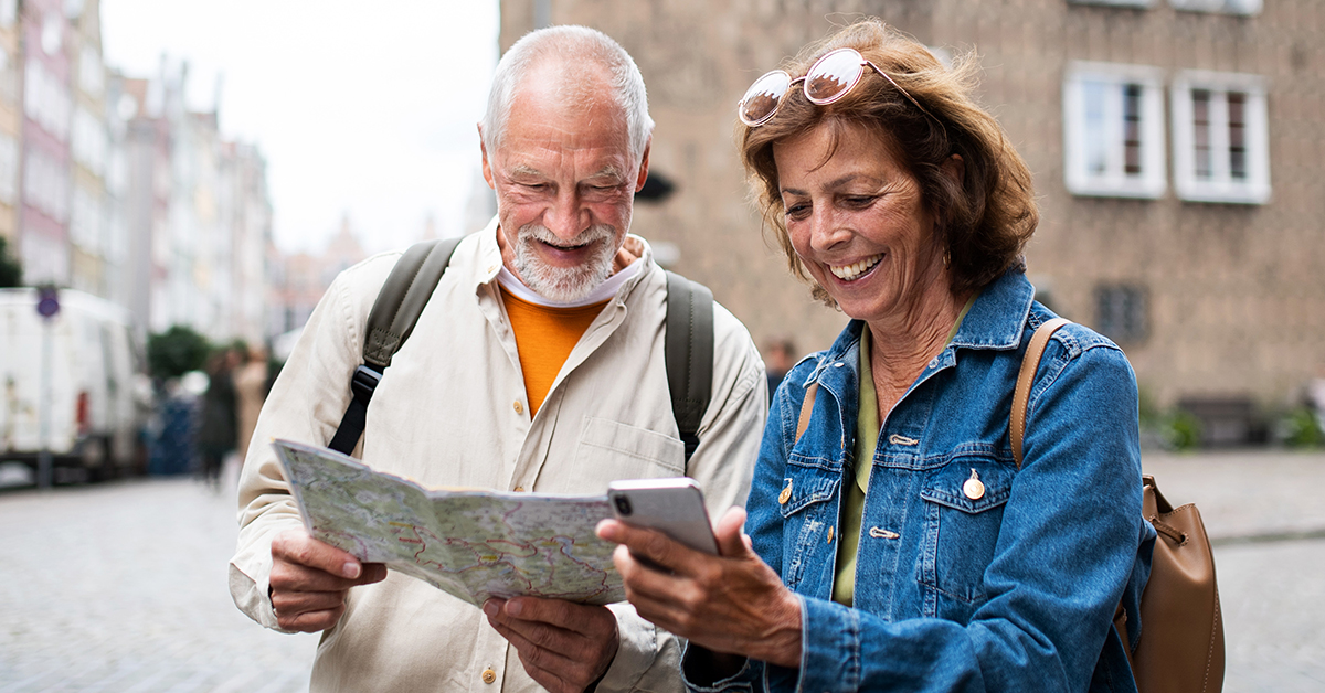 Dwójka seniorów, mężczyzna i kobieta, patrzą na mapę i telefon