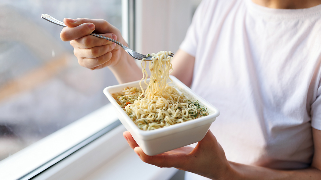 duża porcja zupy z makaronem kobieta w białej bluzce je zupę w domu z makaronem noodle