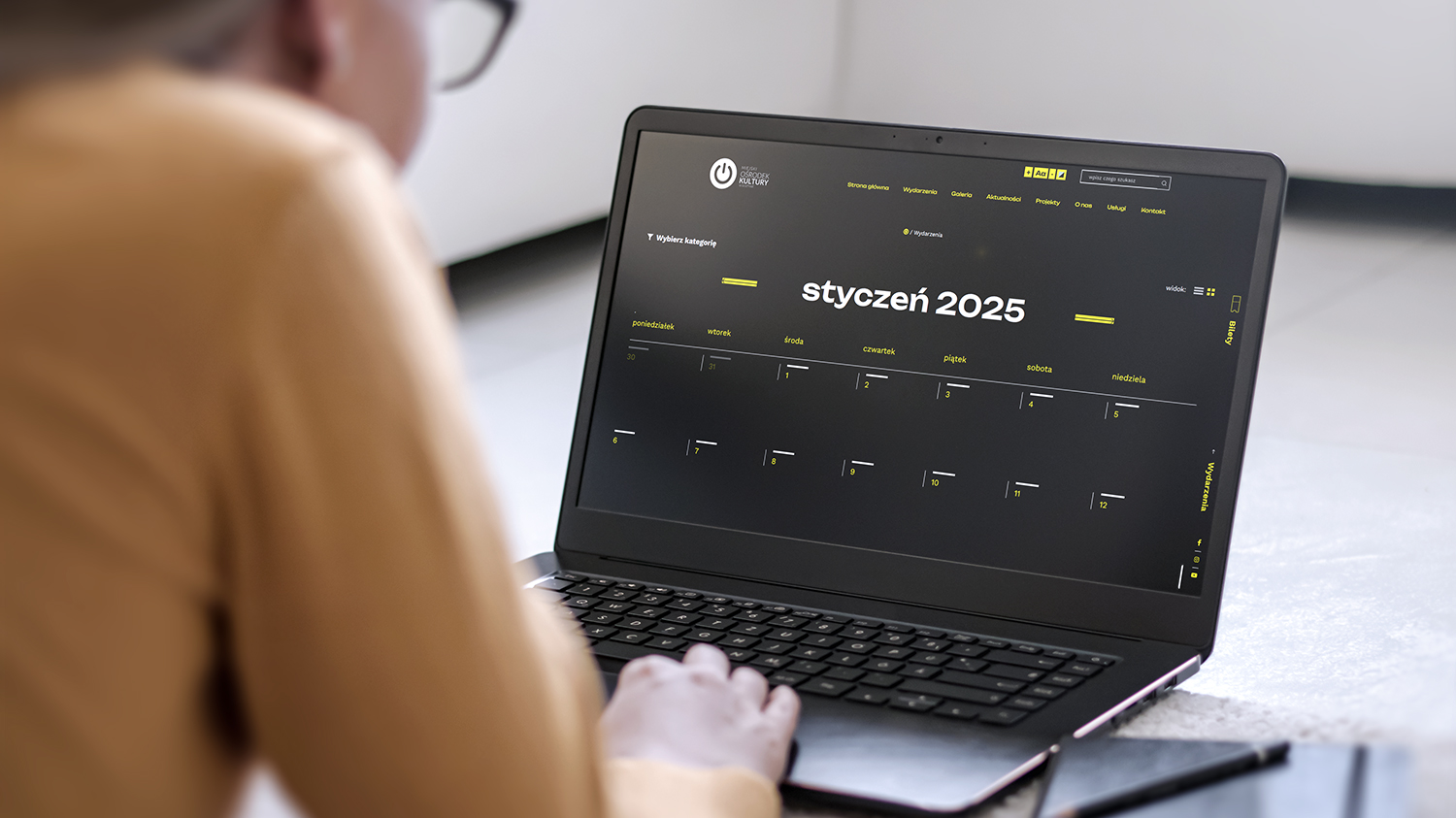 Strona internetowa wyświetlająca kalendarz, którą mężczyzna otworzył na laptopie, dostosowana do osób z kłopotami ze wzrokiem