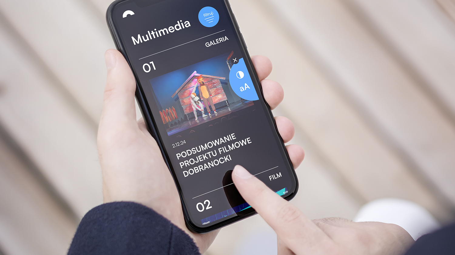 Smartfon trzymany w dłoniach, a na jego ekranie widać opcję dostosowania wielkości czcionki i koloru wyświetlania ekranu.